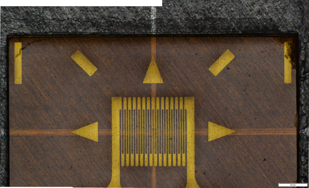 Photograph of a uniaxial strain gage attached to the surface of a metallic part