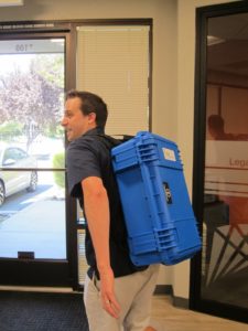 A man with a blue case strapped to his back.