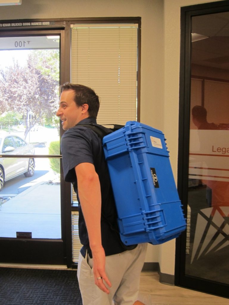 A man with a blue case strapped to his back.